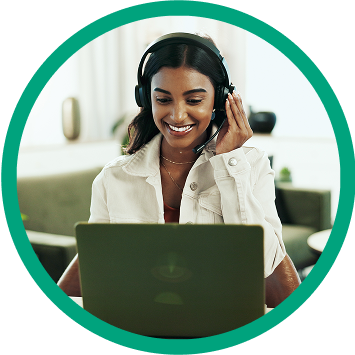 Smiling woman wearing a headset, engaging in a virtual meeting from her laptop at home.